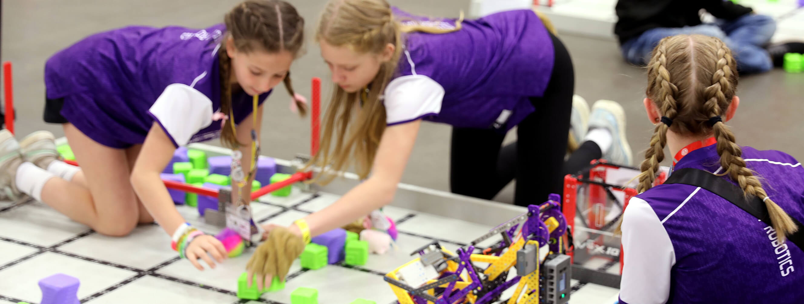 A robotics team of young women studying their robot.